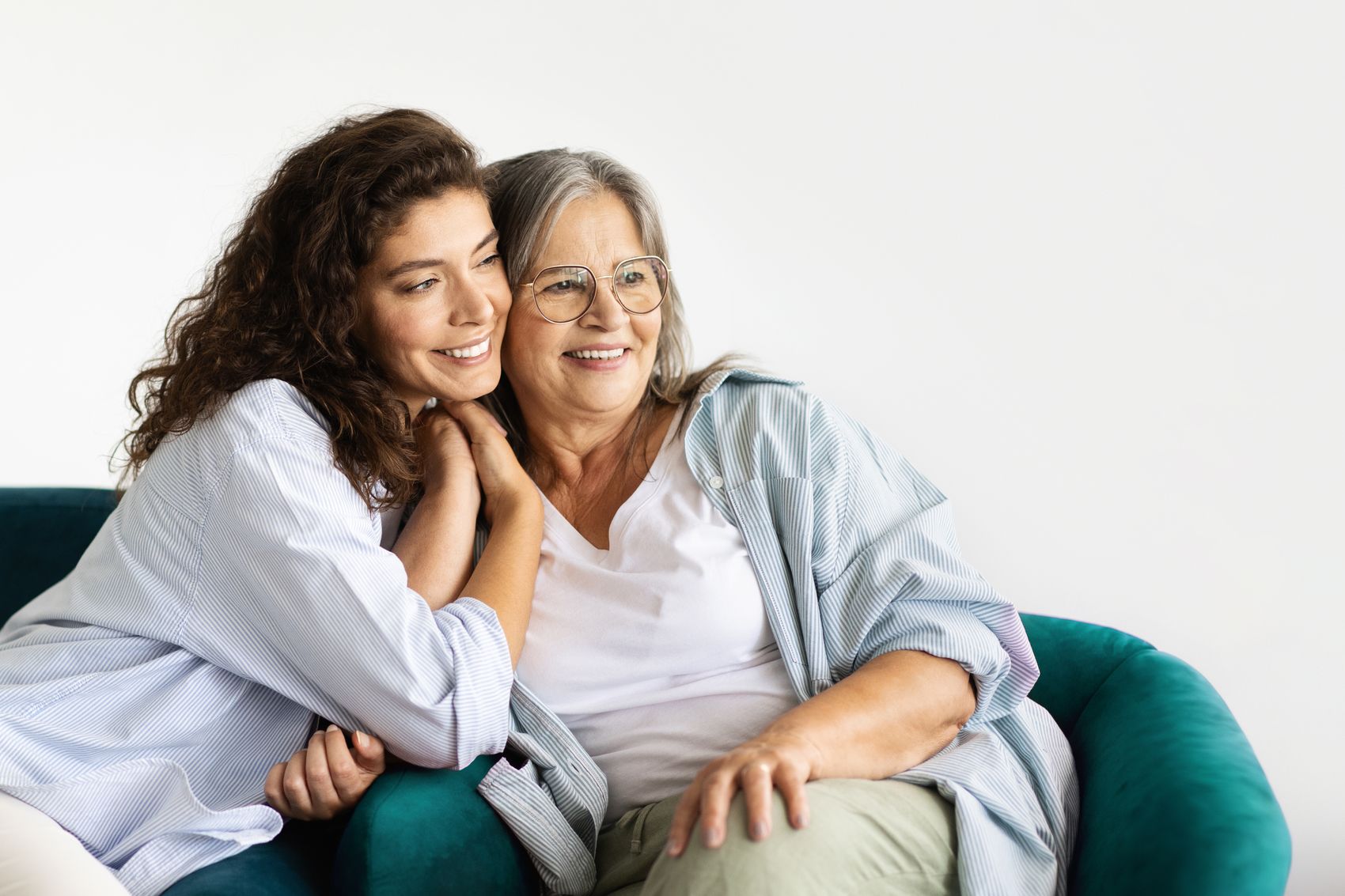 Smiling younger woman hugging her mother on a couch