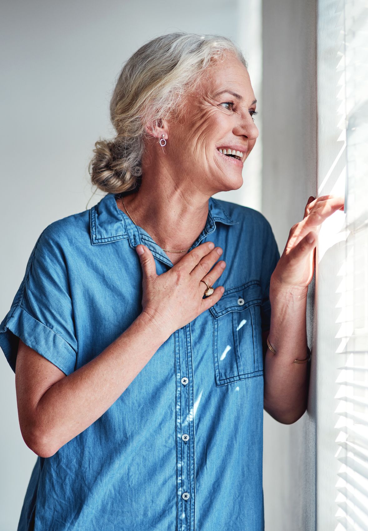 Smiling older woman looking out a sunny window